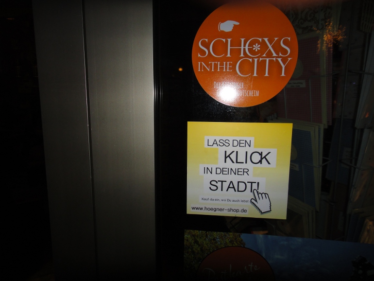 Banner der Kampagne "Lass den Klick in deiner Stadt" im Schaufenster von Schreibwaren Högner.