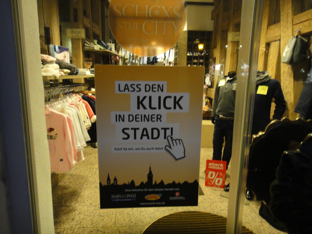 Banner der Kampagne "Lass den Klick in deiner Stadt" im Schaufenster von Polis.