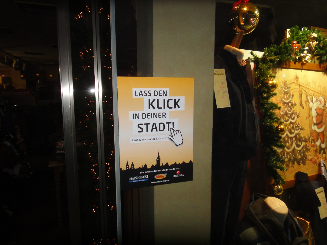 Banner der Kampagne "Lass den Klick in deiner Stadt" im Schaufenster des Modehaus Wiegand.